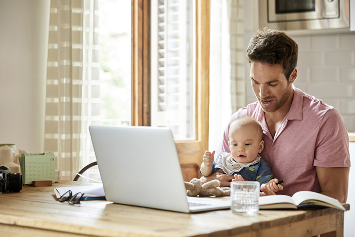 Father holding baby at laptop. Family Finances